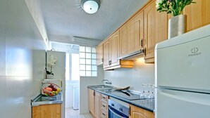 Eine moderne Küche mit Holzschränken, einer Edelstahl-Spüle und einem eingebauten Backofen.
