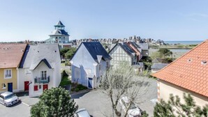 Un quartier résidentiel situé sur la côte, avec des maisons, un phare et une vue sur la mer.