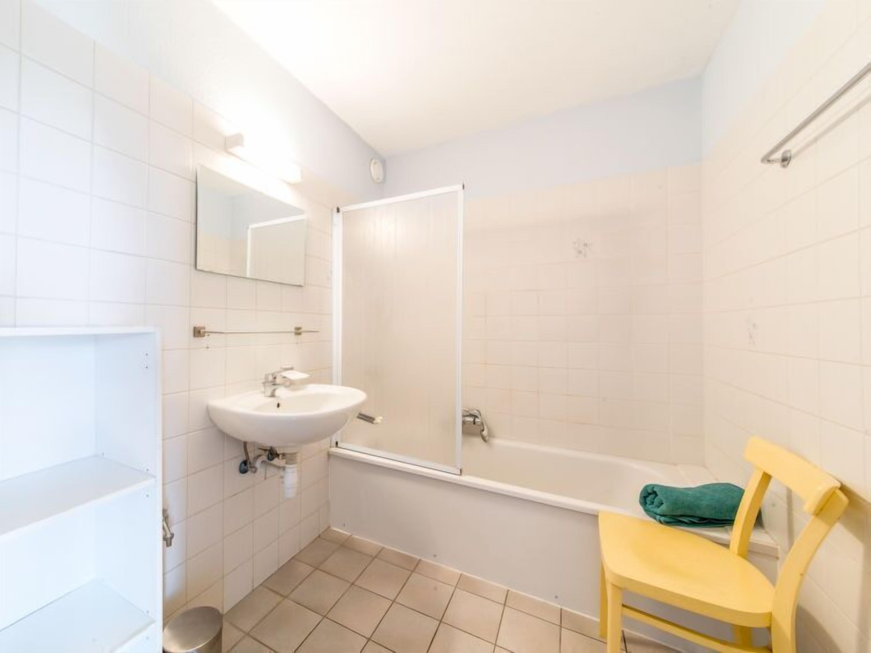 Een badkamer met een wastafel, spiegel en douche.