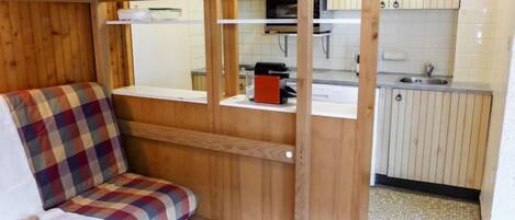 Quarto compacto com beliche, pia de cozinha e pequena área de estar.