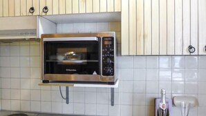 Una cocina con microondas integrado, una botella de vino y una copa sobre la encimera.