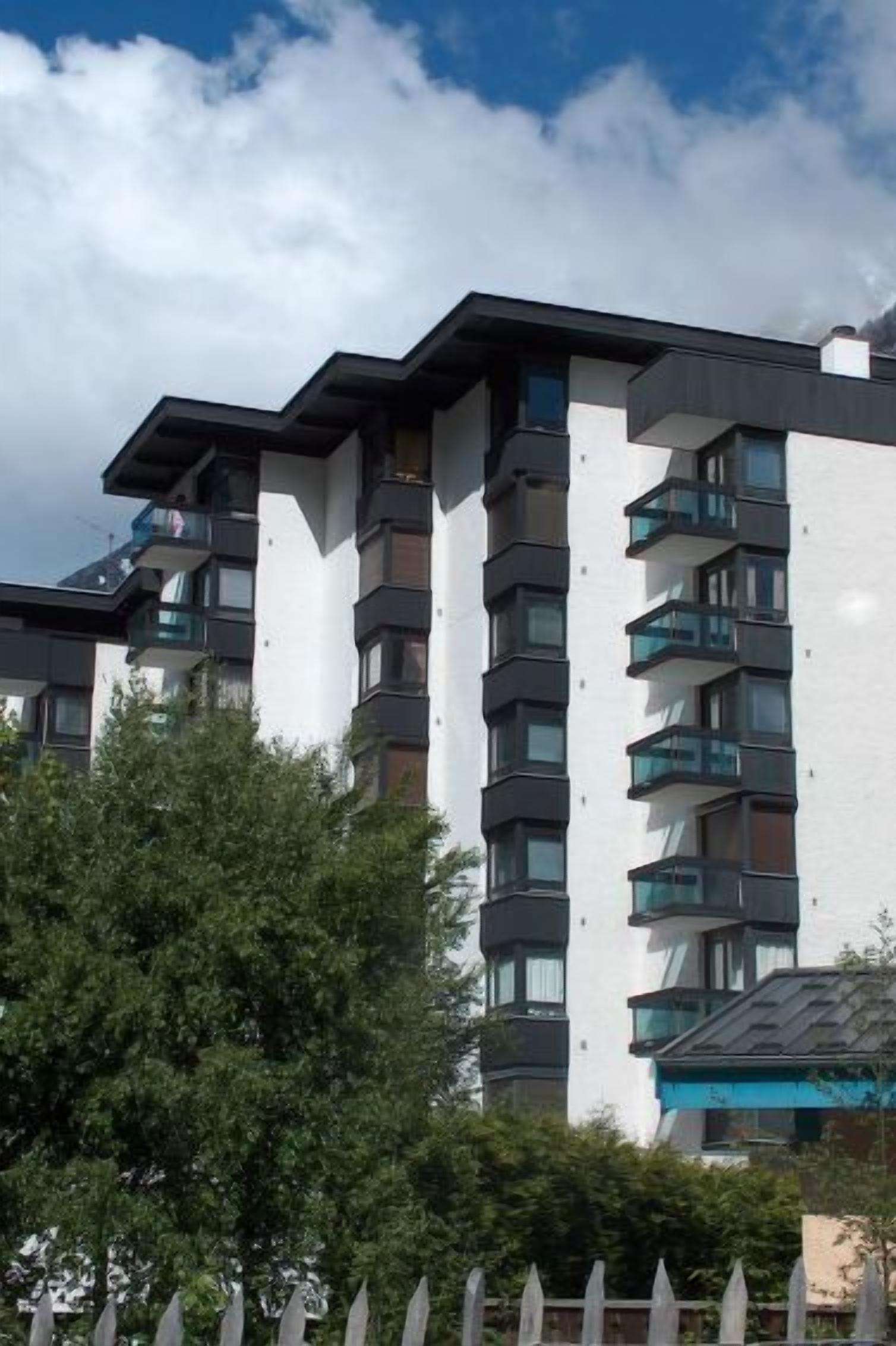 A modern multi-story building with balconies and a white facade.