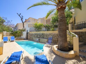A pool area with lounge chairs and a palm tree.