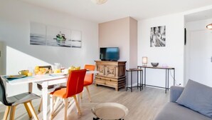 Una sala de estar moderna con comedor, televisor y obras de arte en las paredes.