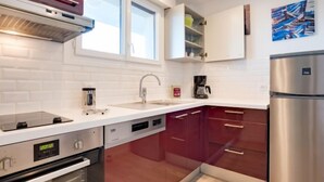 Una cocina moderna con azulejos blancos tipo metro, electrodomésticos de acero inoxidable y un armario rojo.