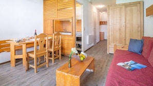 Un espacio habitable compacto con comedor, kitchenette y una zona de estar acogedora.