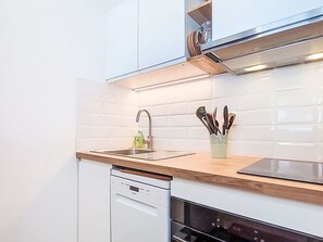 A modern kitchen with white cabinetry, a stainless steel range hood, and a built-in dishwasher. - Névés 150 by Interhome (Val Thorens)