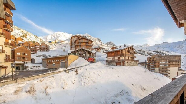 Un pueblo cubierto de nieve en la montaña, con edificios de madera y un cielo despejado.