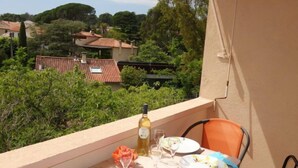 A balcony with a table set for two, overlooking a residential area with houses and trees. - Les Vignes by Interhome (Saint Cyr sur mer Les Lecques)
