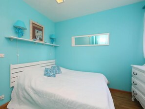 A bedroom with a bed, a dresser, a mirror, and a shelf with decorative items. - Le Garden by Interhome (Cabourg)