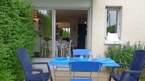 An outdoor patio with a table set for four, surrounded by blue chairs. - Le Garden by Interhome (Cabourg)