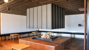 Ein modernes Interieur mit Kamin, Holzbanken und Fliesenboden.
