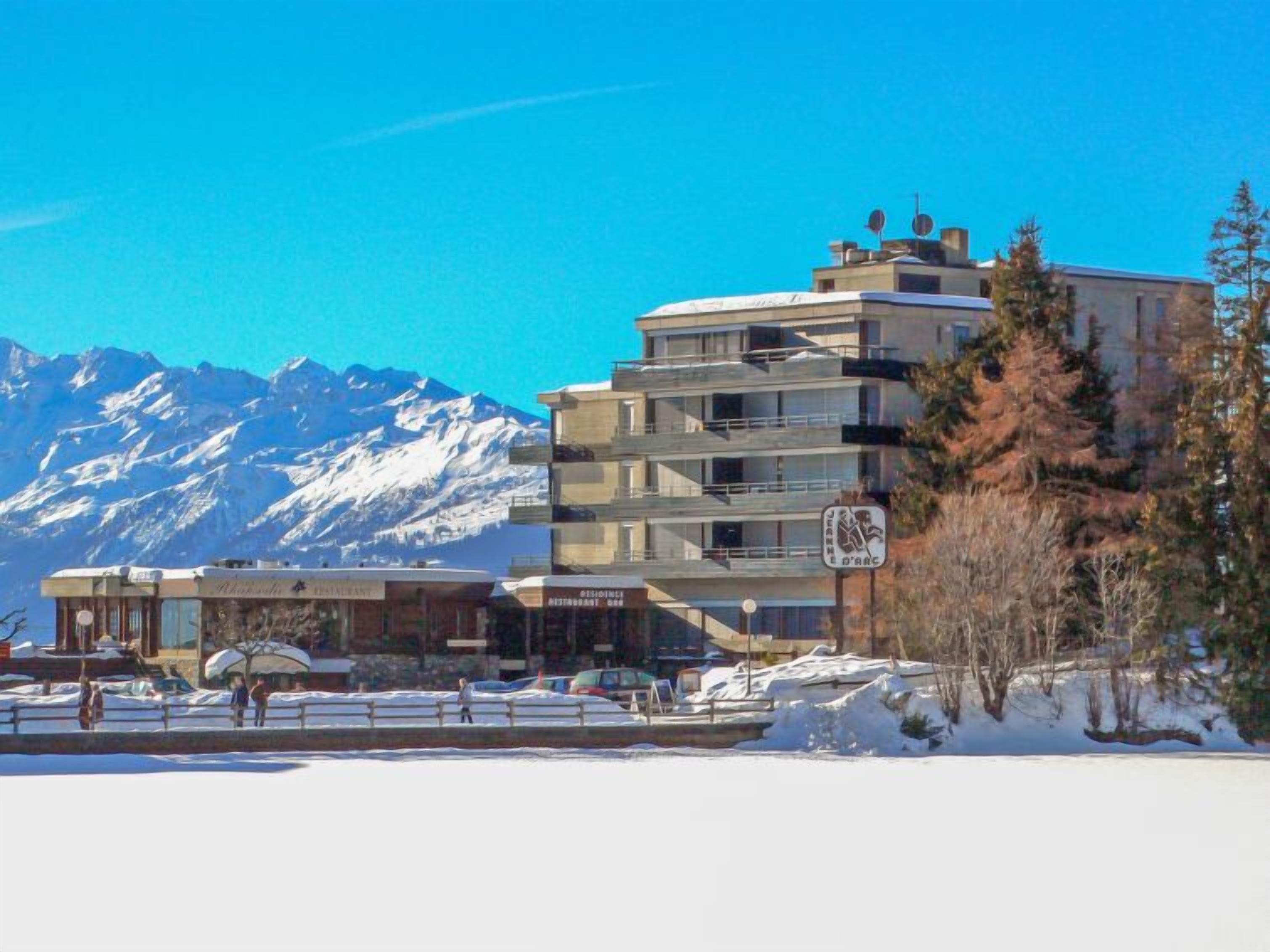 A multi-story hotel with a view of snow-covered mountains in the background.