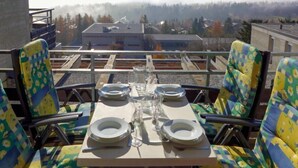 Ein Tisch für zwei Personen mit Stühlen, mit Blick auf eine Berglandschaft, einschließlich eines Gebäudes und Bäumen.