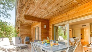 A wooden deck with a dining table and chairs, a grill, and a view of the surrounding trees. - Cala Sultana by Interhome (Porto Vecchio)