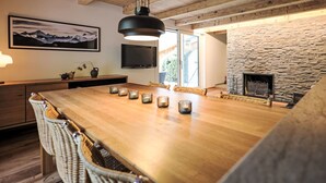 A modern kitchen with a wooden island, a stone wall, and a television mounted on the wall. - Chalet Butz by Interhome (Grindelwald)