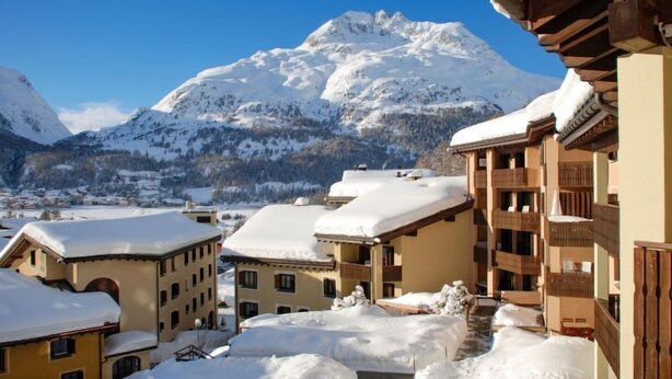 Un pueblo cubierto de nieve con edificios tradicionales de madera y una vista despejada de la montaña al fondo.