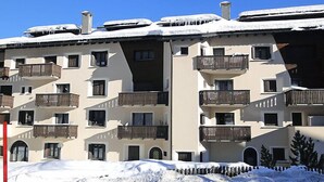 A multi-story hotel with balconies, snow-covered roofs, and a clear blue sky. - Apartment Apt.17 by Interhome (Silvaplana-Surlej)