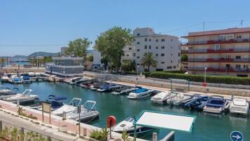 Un puerto deportivo con barcos amarrados, un edificio con balcones y cielo despejado.