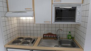Kompakti keittiö, jossa on liesi, mikroaaltouuni, pesuallas ja astianpesukone.
