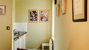 Una cucina compatta con angolo ristoro, caratterizzata da un pavimento piastrellato, un lavandino e un piccolo tavolo con sedie.