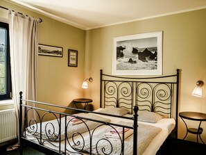 Cozy retreat with a metal-framed bed, bedside table, and window with a curtain.