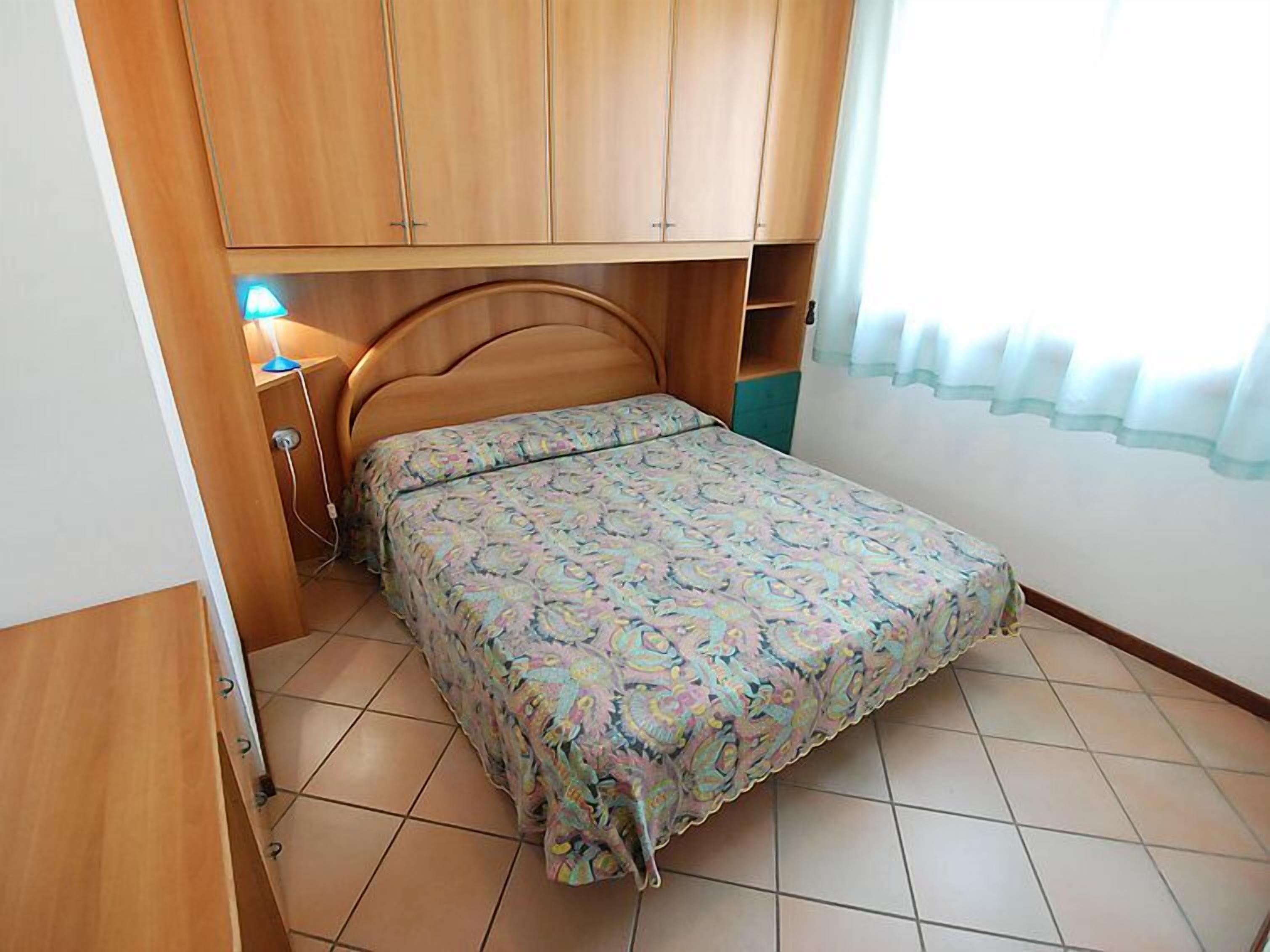 Une chambre à coucher avec un lit, une armoire en bois et une table de chevet avec une lampe.
