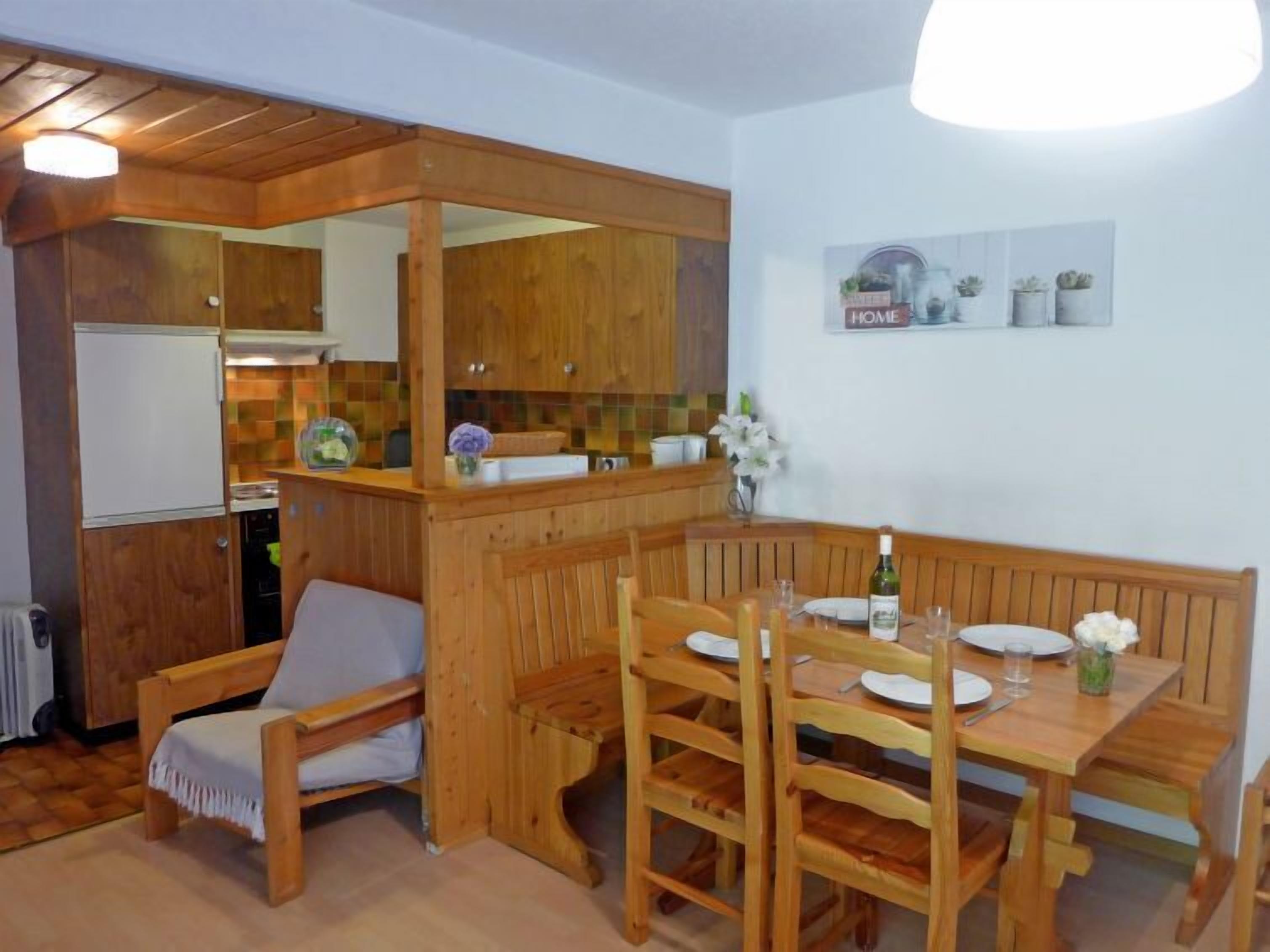 A cozy kitchen with wooden cabinets and a dining area with a bench and table.