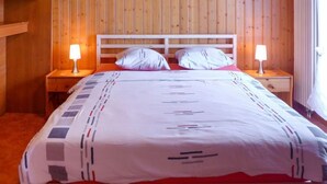 Una habitación con paneles de madera, una cama, dos mesitas de noche con lámparas y un cuadro en la pared.
