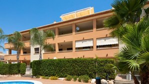 Un hôtel à plusieurs étages doté d’une piscine, de palmiers et d’un jardin bien entretenu.