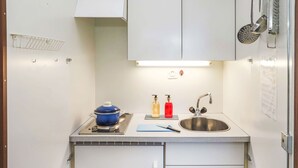 A compact kitchen with white cabinets, a stainless steel sink, a blue pot on a portable stove, and two soap dispensers. - Rosablanche D35 by Interhome (Siviez-Nendaz)
