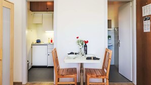 A dining area with a white table set for two, wooden chairs, and a vase with flowers. - Rosablanche D35 by Interhome (Siviez-Nendaz)