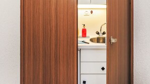 A wooden door leading to a kitchen with a sink, a red soap dispenser, and a white countertop. - Rosablanche D35 by Interhome (Siviez-Nendaz)