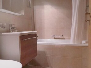 A bathroom with a sink, mirror, cabinet, and bathtub. - Apartment Select by Interhome (Zermatt)