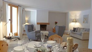 Un salon moderne avec une cheminée, un coin salon et une table à manger dressée pour le repas.