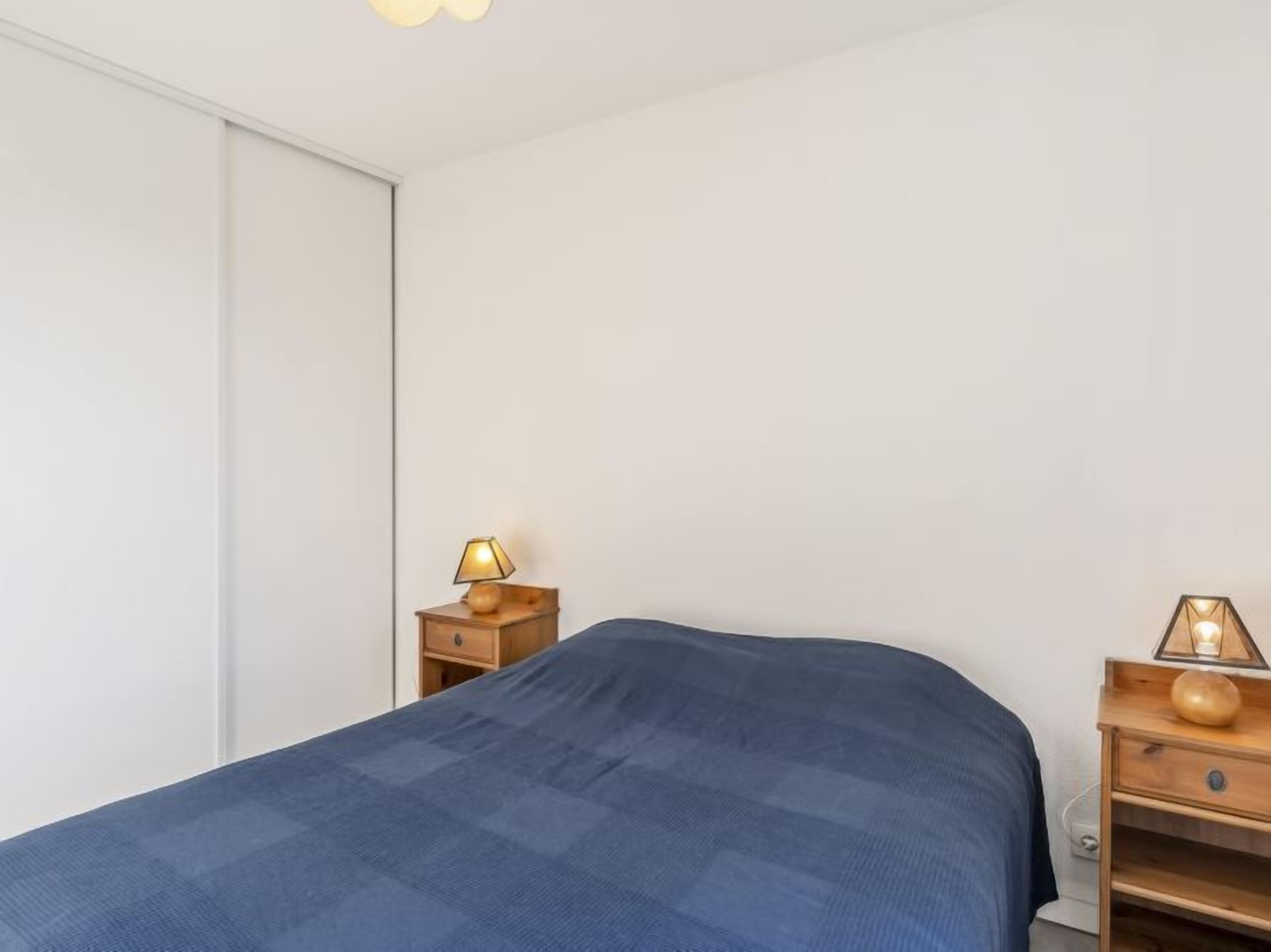Ein Schlafzimmer mit einem Bett, einem Nachttisch mit Lampe und einem Kleiderschrank.