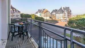 Ein Balkon mit Tisch und Stühlen, mit Blick auf eine Straße mit Gebäuden im traditionellen europäischen Stil.