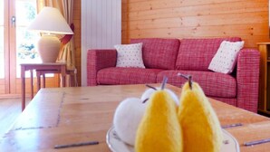 Una stanza accogliente con un tavolo di legno, un divano rosso a quadretti e una lampada.