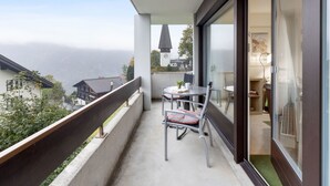 Uma varanda com mesa e cadeiras, com vista para uma paisagem montanhosa.