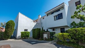 Un immeuble résidentiel moderne à deux étages, avec une façade blanche et un toit recouvert de tuiles rouges.