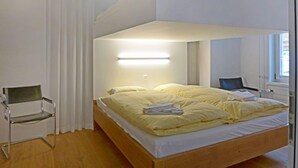 A modern bedroom with a wooden bed, white curtains, and a bedside table. - Haus Lauber Apt.1 by Interhome (Wengen)
