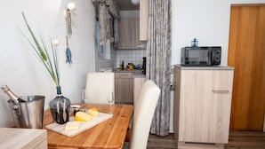 Una cocina funcional con una mesa de madera, microondas y un mueble pequeño.