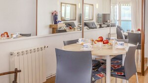 Zona pranzo con tavolo rotondo, sedie e uno specchio che riflette l'ambiente.