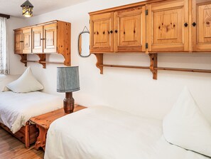 Ein Zimmer mit zwei Betten, Holzschränken, einer Lampe und einem Wandspiegel.