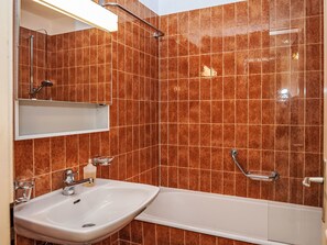 Ein Badezimmer mit weißem Waschbecken, Spiegel und Dusche.