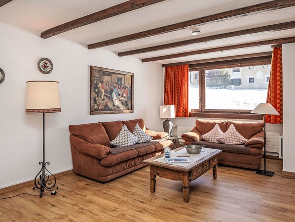 Ein gemütliches Wohnzimmer mit zwei braunen Sofas, einem Holztisch und einem Bild an der Wand.