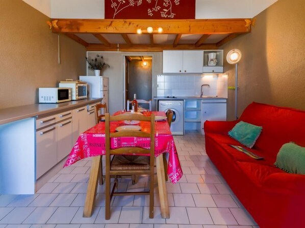 Une cuisine compacte avec une table à manger, un canapé rouge et un lave-linge.