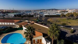 Zona residencial con piscina, palmeras y un puerto deportivo al fondo.