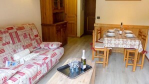 A cozy living room with a sofa, a dining table set for two, and a wooden cabinet. - Clos du Savoy by Interhome (Chamonix)