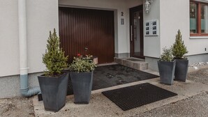 A building entrance with a dark wooden door, a blue sign with the number 2, and two potted plants on the steps. - Rudis Appartements by Interhome (Bad Gastein)